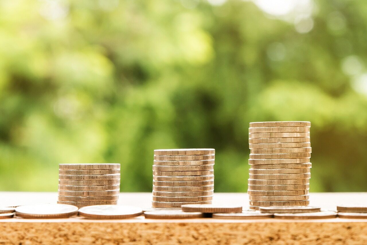 Three stacks of coins against a softly blurred green background.
